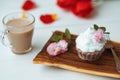 Cake and Coffee. Tasty cake with cream and pink flower decor in wooding plate. Red flowers on background