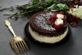 Cake covered with chocolate decorated raspberries, with a bouquet of flowers on a gray background.