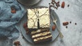 Cake with cream and dark chocolate biscuit. Served in squares on a plate with coffee in cup