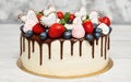 Cake decorated with Chocolate Fresh Berries and Cookies. White Cake Design with Decoration on top over Abstract Background