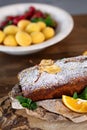 Cake is decorated with dried fruits, orange and mint, next to it is plate with apricots, selective focus, homemade cakes in