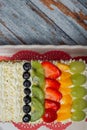 Cake decorated with fruit served on a white platter. Wooden background. Royalty Free Stock Photo