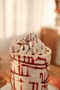 The cake is decorated with skulls and blood for Halloween. Kitchen is decorated for autumn