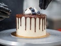 cake designer decorating a chocolate drip cake with mering and blueberries Royalty Free Stock Photo
