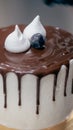 cake designer decorating a chocolate drip cake with mering and blueberries Royalty Free Stock Photo