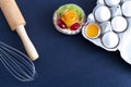 Cake, eggs in a tray with a rolling pin and a whisk on the table Royalty Free Stock Photo
