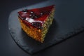 Cake with fruity cream and pistachio decorated with nuts, isolated on black stone