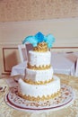 The cake has blue feathers and a golden crown . White three-tiered cake