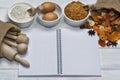 Cake ingredients, hazelnuts and wooden kitchen utensils on a white wooden table. An empty notebook as a place for your text. Royalty Free Stock Photo