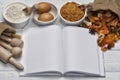 Cake ingredients, hazelnuts and wooden kitchen utensils on a white wooden table. An empty notebook as a place for your text. Royalty Free Stock Photo