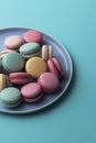 Cake macaron or macaroon on plate close-up from above, blue background, colorful almond cookies, pastel colors, greeting card, top