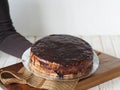 Cake making process. Women is hands hold a freshly made homemade Enchantress cake, covered with chocolate icing