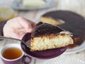 Cake making process. Women is hands serve a piece of freshly made homemade Enchantress cake covered with chocolate icing