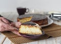 Cake making process. Women is hands serve a piece of freshly made homemade Enchantress cake covered with chocolate icing