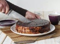 Cake making process. Women is hands cut a freshly made homemade Enchantress cake covered with chocolate icing into pieces for