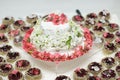 Cake with natural white and pink tree flowers surrounded by cakes close up on white background