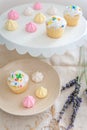 A cake plate and dessert plate filled with confetti sprinkled cupcakes and pastel colored meringue bite cookies.