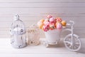 Cake pops in decorative bicycle and candles on white wooden ba