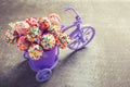 Cake pops in decorative bicycle on grey slate background.