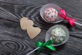 Cake pops in white glazed chocolate with green and pink sprinkles. A green and pink bow is tied on sticks. Nearby hearts cut out