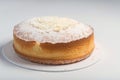 a cake with powdered sugar on top on a white plate on a white tablecloth with a white border around the edge of the cake