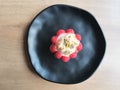 Cake with raspberries on a black plate and a wooden table. Cooking sweets at home.