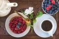 Cake with raspberries, bowl with blackberries and cup of coffee on beautiful vintage plate.