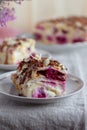 Cake from rolled pancakes with custard, cherries and grated chocolate on white plate, on a light background.