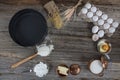 Cake in rural kitchen - dough recipe ingredients eggs, flour, milk, butter, sugar and rolling pin on vintage wooden table from Royalty Free Stock Photo