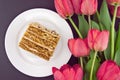 Cake slice with nut on plate. Bouquet of tulips. Top view Royalty Free Stock Photo