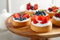 Cake stand with different berry tarts on table