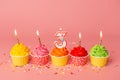 Cake for the third birthday. Candle number 3 in a cupcake among colorful cakes on a pink background Royalty Free Stock Photo