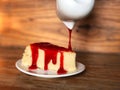 Cake topped with strawberry sauce in white dish on the wooden