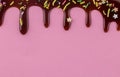 Cake topping coloured sprinkles with chocolate flowing down on pink background Royalty Free Stock Photo