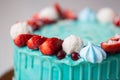 Cake turquoise and blue with strawberries, meringue and candies.