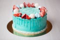 Cake turquoise and blue with strawberries, meringue and candies.