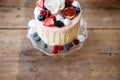 Cake with various berries, figs, meringues and rose on top.