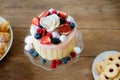 Cake with various berries, meringues and rose on cakestand. Royalty Free Stock Photo