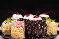 Cakes with chocolate, cherries and cream on a black background.