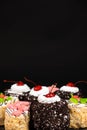 Cakes with chocolate, cherries and cream on a black background, place for text