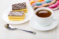 Cakes with chocolate on plate, napkin, tea, teaspoon on table