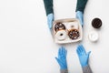 Cakes for customer at home and order issue. Client in rubber gloves takes box with donuts with chocolate and white