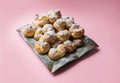 Cakes profiteroles sprinkled with powdered sugar on a pink background. Homemade eclairs.