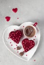 Cakes Red velvet in the shape of hearts on white plate and cup of coffee for Valentines Day on light gray background Royalty Free Stock Photo