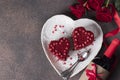 Cakes Red velvet in the shape of hearts on white plate, roses and bottle wine for Valentines Day on brown background Royalty Free Stock Photo