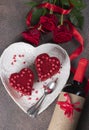 Cakes Red velvet in the shape of hearts on white plate, roses and wine for Valentines Day on brown background, vertical Royalty Free Stock Photo