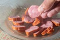Calabresa sausage sliced on a plate with hand holding a slice,simple concept of cold cuts,Brazilian calabresa Royalty Free Stock Photo