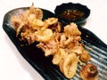 Calamari & x28;fried squids& x29; with spicy sauce on black ceramic plate Royalty Free Stock Photo