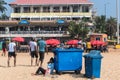 Blue trash cans on a crowded tourist beach in the town of Calangute in Goa