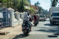 CALANGUTE, GOA, INDIA JANUARY 2, 2019: Motorcyclists and cars with passengers on street in India. Sunny day, moderate traffic
